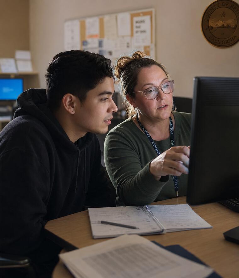 A caseworker and a jobseeker sitting side by side, looking at the same screen